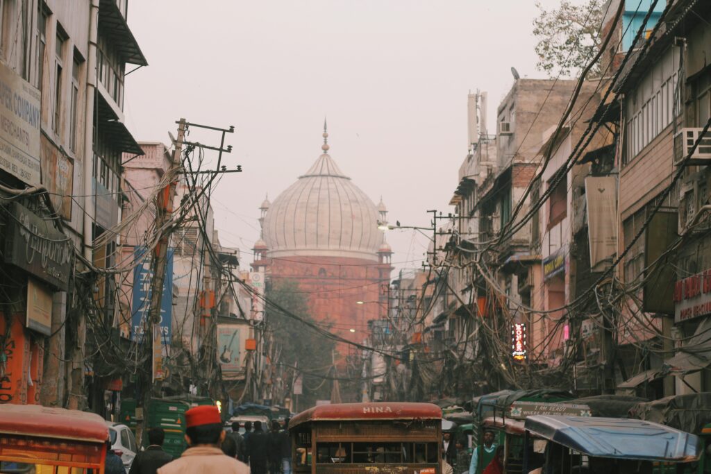 Street in India filled with wires and shop signs with temple in the background