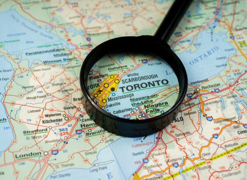 Magnifying glass zooming into Toronto on a world map