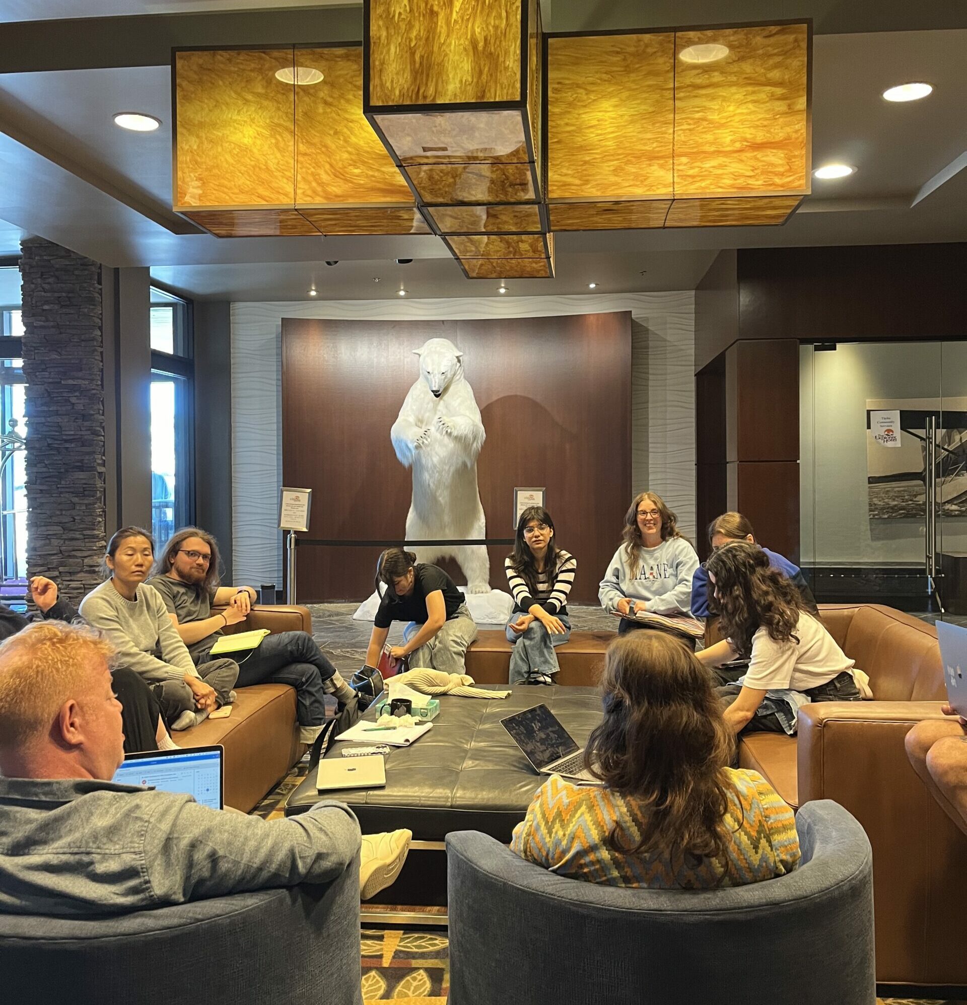 Group talks in meeting space with taxidermied polar bear in background