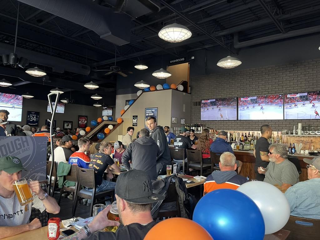 People at restaurant tables watching hockey game on television