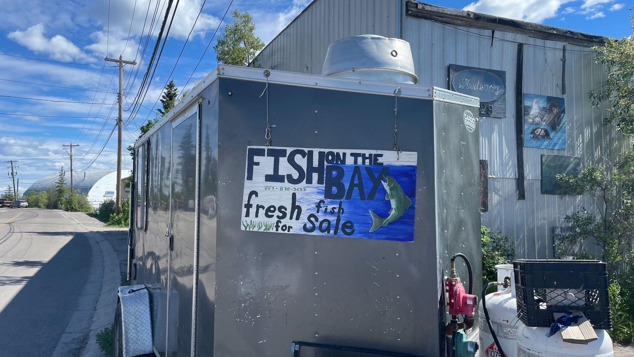 An outdoor sign written with "Fish on the bay; fresh fish for sale"