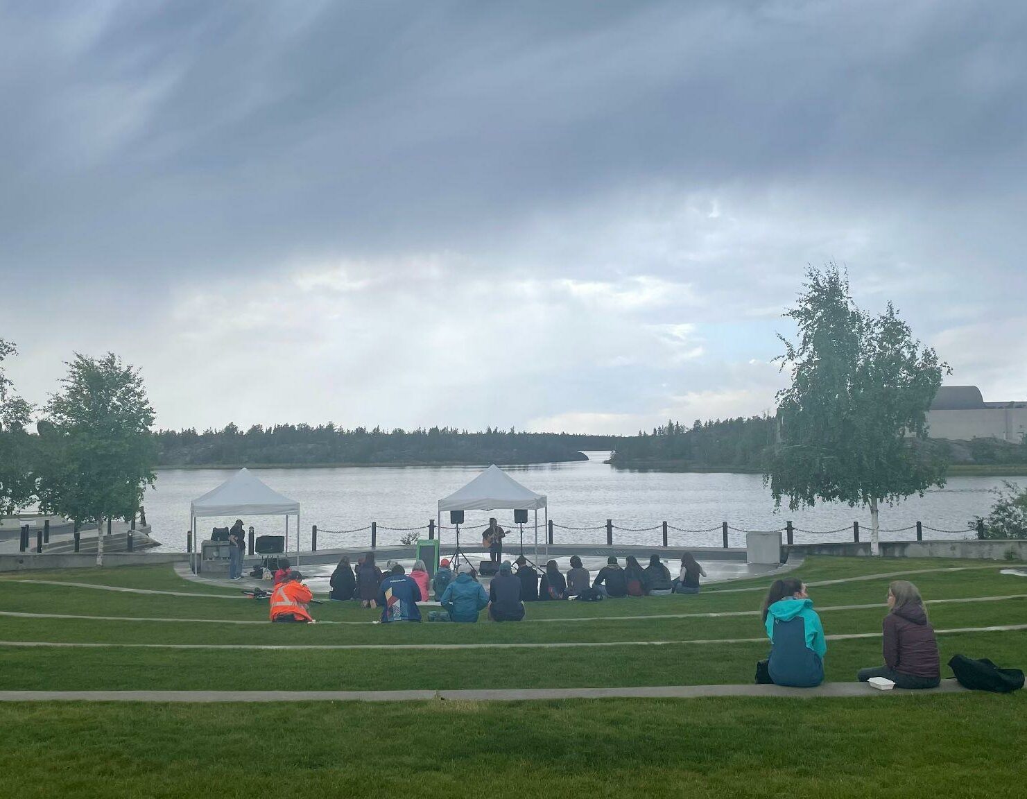 Musician playing on outdoor stage as audience watches on