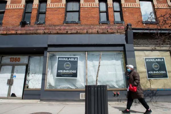 a person walking by unoccupied retail space on queen st